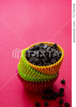 Baking abstract concept. Colored paper baking cups for cupcakes or muffins. Red background. Baking abstract concept. Colored paper baking cups for cupcakes or muffins. Red background. 71730346