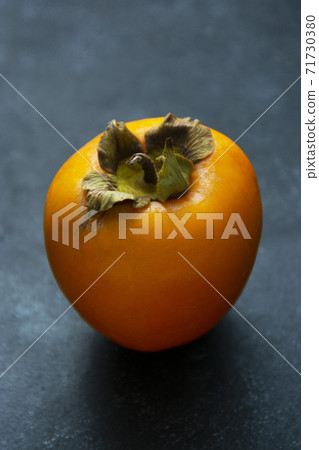 Whole sweet orange persimmon fruits isolated on dark background. Copy space. 71730380
