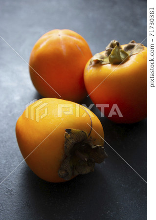 Whole sweet orange persimmon fruits isolated on dark background. Copy space. 71730381