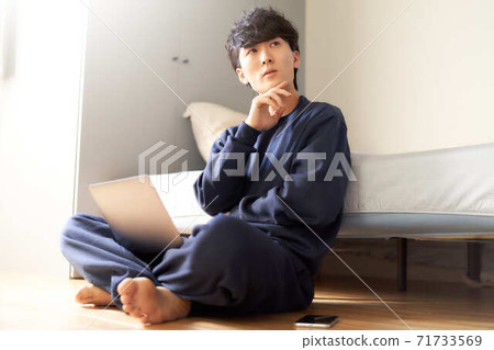 A man thinking with his PC on his lap in the bedroom A man thinking with his PC on his lap in the bedroom 71733569