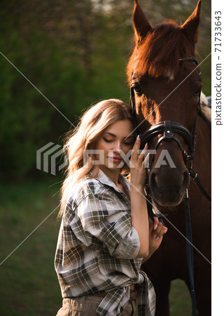 Beautiful girl with her horse and beautiful warm sunset in the spring forest. Beautiful girl with her horse and beautiful warm sunset in the spring forest. 71733643