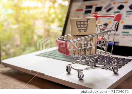 Shopping online concept - Parcel or Paper cartons with a shopping cart logo in a trolley on a laptop keyboard. Shopping service on The online web. offers home delivery.. 71734071