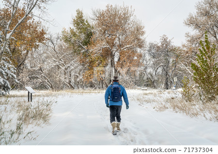 senior male is walking on a trail with fresh snow 71737304