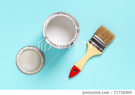 New natural bristle brush with wooden handle, open white paint can and lid on a cyan blue background 71738909