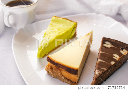 Set of New York, chocolate and pistachio cheesecake on white plate and cup of coffee Set of New York, chocolate and pistachio cheesecake on white plate and cup of coffee 71739714