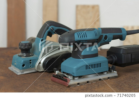 Electric planer and electric sheet finishing sander on old rusty metal sheet, on background oriented strand board Electric planer and electric sheet finishing sander on old rusty metal sheet, on background oriented strand board 71740205