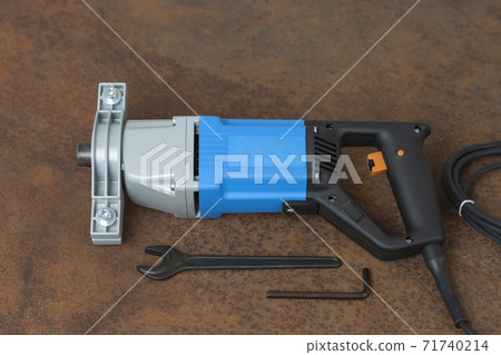 Wrench and mixing drill for mixing of mortar, paint , plaster and powder on old rusty metal sheet. 71740214