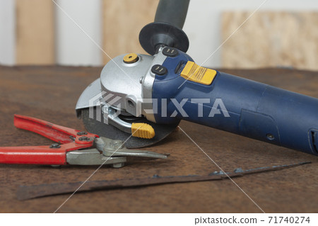 Angle grinder with thinner cut-off disc and red shears for cutting metal on  old rusty metal sheet. 71740274