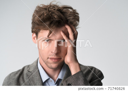 Young sad thoughtful man having headache after work. Exhausted young man working a lot and touching his head, he is having a headache, stress and overwork 71740826