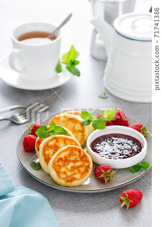 Cottage cheese pancakes, sweet curd fritters with berries, syrniki with jam and fresh raspberry on breakfast table Cottage cheese pancakes, sweet curd fritters with berries, syrniki with jam and fresh raspberry on breakfast table 71741386