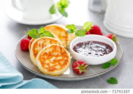 Cottage cheese pancakes, sweet curd fritters with berries, syrniki with jam and fresh raspberry on breakfast table Cottage cheese pancakes, sweet curd fritters with berries, syrniki with jam and fresh raspberry on breakfast table 71741387