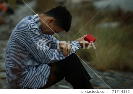 A man holding a ring case and shedding tears A man holding a ring case and shedding tears 71744385