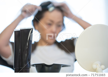 Woman applying self-hair color 71751083
