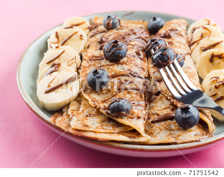 Crepes with chocolate nut spread, banana, berries Crepes with chocolate nut spread, banana, berries 71751542