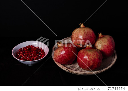 Pomegranate in wooden plate and seeds in white bowl Pomegranate in wooden plate and seeds in white bowl 71753654