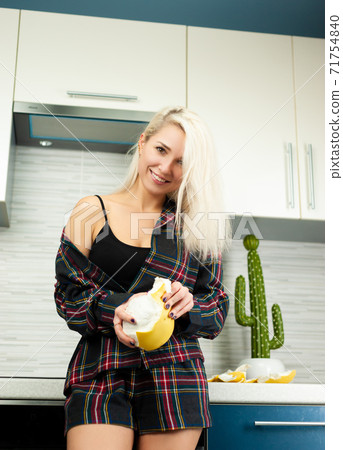 Woman in the kitchen in home clothes cleaning fruit pomelo with emotions Woman in the kitchen in home clothes cleaning fruit pomelo with emotions 71754840