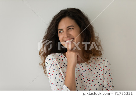Smiling young woman isolated on grey background dreaming 71755331