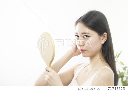 Beauty image A woman who looks in the mirror and repairs her hair Beauty image A woman who looks in the mirror and repairs her hair 71757325