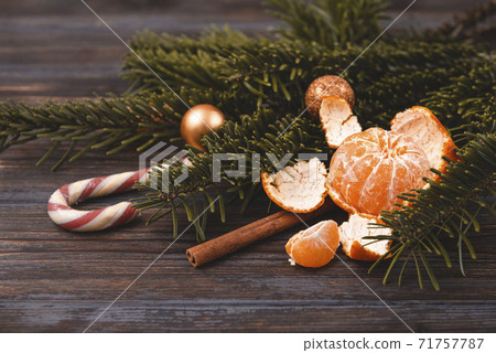tangerine,  Lollipop, cinnamon stick, spruce branch, Golden Christmas balls on a dark wooden 71757787