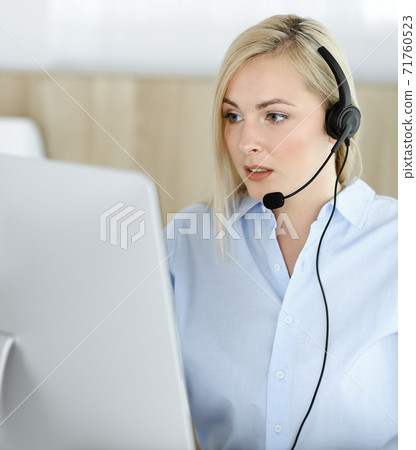 Blonde business woman sitting and communicated by headset in call center office. Concept of telesales business or home office occupation 71760523