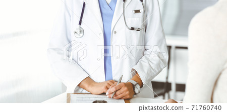 Unknown woman-doctor sitting and communicating with female patient. Physician checks medical history record and exam results, close-up. Healthcare concept Unknown woman-doctor sitting and communicating with female patient. Physician checks medical history record and exam results, close-up. Healthcare concept 71760740