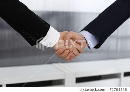 Businessman and woman shaking hands in office. Concept of handshake as success symbol in business 71761328