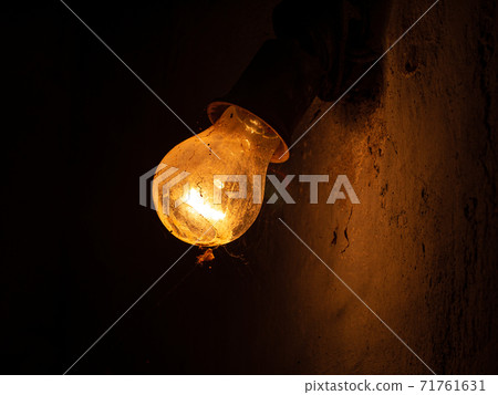 Old bulb lamp glowing in the dark. Dusty vintage lights decor wall. Retro style yellow bulbs. Idea and teamwork concept Old bulb lamp glowing in the dark. Dusty vintage lights decor wall. Retro style yellow bulbs. Idea and teamwork concept 71761631