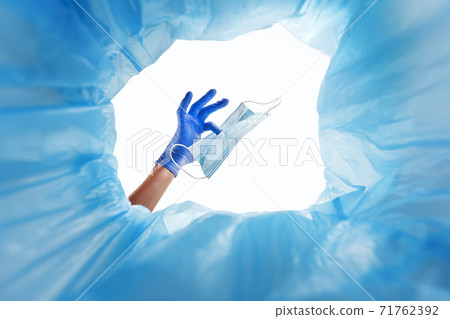 Disposal of the used protective medical mask in the waste container. Disposal of the used protective medical mask in the waste container. 71762392