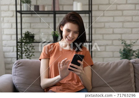 Happy young caucasian woman using mobile phone at home. 71763296