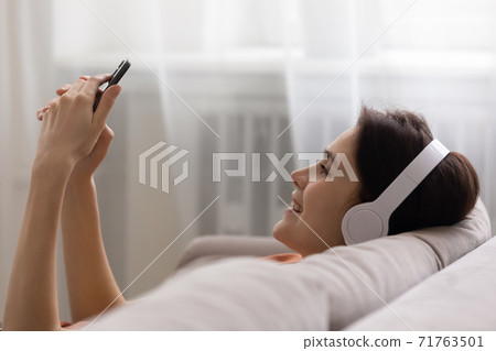 Smiling woman listening music choosing tracks in mobile application. 71763501