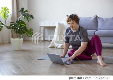 Senior woman prepares for workouts on the Internet. Senior woman prepares for workouts on the Internet. 71765078