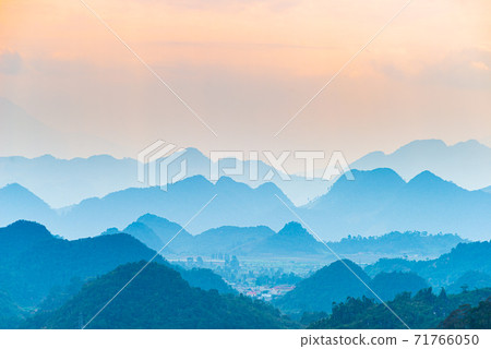 Ha Giang karst geopark landscape in North Vietnam. Mountain silhouette stunning scenery mist and fog in the valleys at sunset. Ha Giang motorbike loop, famous travel destination bikers easy riders. Ha Giang karst geopark landscape in North Vietnam. Mountain silhouette stunning scenery mist and fog in the valleys at sunset. Ha Giang motorbike loop, famous travel destination bikers easy riders. 71766050
