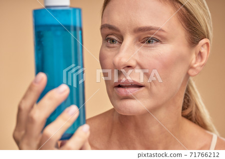 Pretty adult lady going to use anti-aging lotion Pretty adult lady going to use anti-aging lotion 71766212