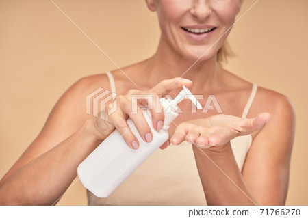 Smiling pretty woman holding bottle with cream lotion Smiling pretty woman holding bottle with cream lotion 71766270
