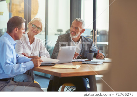 Three mature colleagues sitting in the modern office and discussing business strategy, business people working together Three mature colleagues sitting in the modern office and discussing business strategy, business people working together 71766273