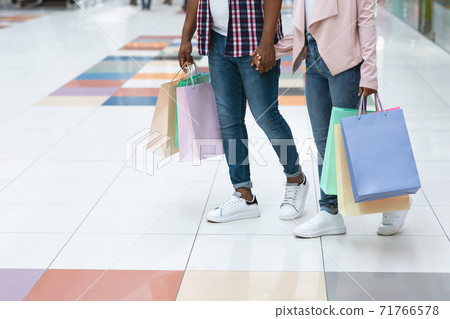 Unrecognizable African Couple Walking In Mall, Carrying Bright Shopping Bags, Cropped Image Unrecognizable African Couple Walking In Mall, Carrying Bright Shopping Bags, Cropped Image 71766578