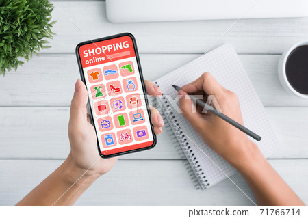 Woman Shopping Online On Mobile Phone And Taking Notes, Closeup 71766714