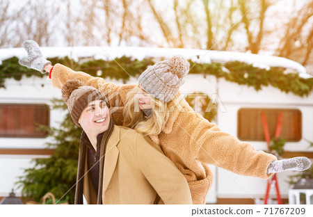 Cheerful millennial couple having fun outside at winter camping, woman piggybacking boyfriend 71767209