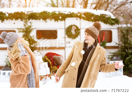 Snow Fight. Joyful millennial couple having fun, throwing snowballs at each other Snow Fight. Joyful millennial couple having fun, throwing snowballs at each other 71767222