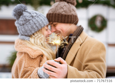 Romantic Young Couple Holding Sparkler And Embracing Outdoors At Winter Day 71767316
