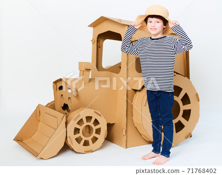 A little boy is playing with cardboard tractor on a white background. Agriculture concept. Mockup for design with copy space. 71768402