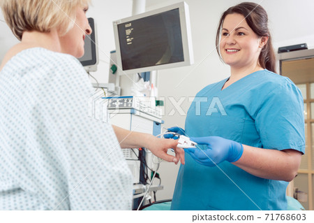 Nurse preparing blood pressure sensor for surgery on patient 71768603