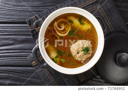 Delicious Viennese rindsuppe soup based on beef broth with dumplings close-up in a saucepan. horizontal top view Delicious Viennese rindsuppe soup based on beef broth with dumplings close-up in a saucepan. horizontal top view 71768952