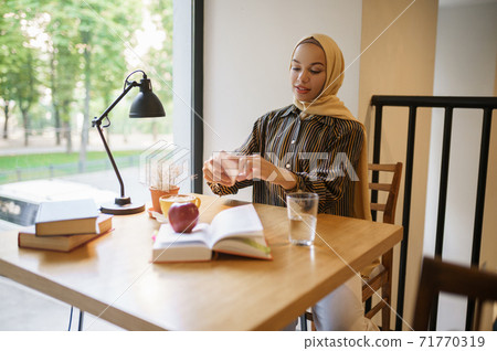 Arab girl makes photo of cup with coffee Arab girl makes photo of cup with coffee 71770319