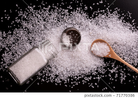 Salt shaker with salt and wooden spoon top view. 71770386