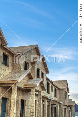 Construction of townhouses viewed against blue sky and clouds on a sunny day Construction of townhouses viewed against blue sky and clouds on a sunny day 71771434