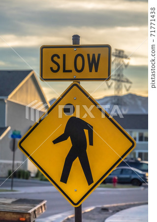 Pedestrian crossing road sign against houses vehicles mountain and cloudy sky Pedestrian crossing road sign against houses vehicles mountain and cloudy sky 71771438