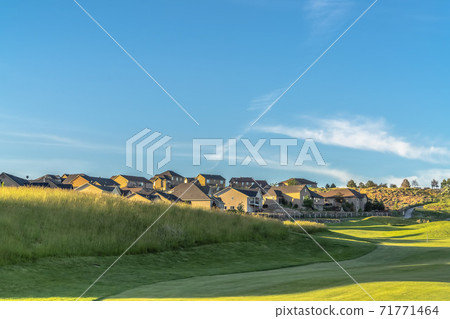 Scenic sunny day view of houses around a golf course with blue sky overhead Scenic sunny day view of houses around a golf course with blue sky overhead 71771464