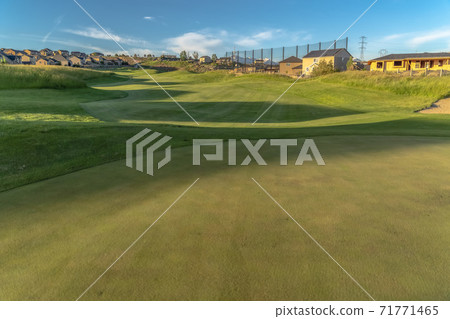 Scenic view of houses around a golf course under blue sky on a sunny day Scenic view of houses around a golf course under blue sky on a sunny day 71771465