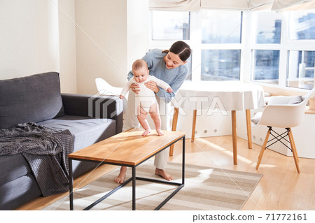 Mother holding her son while he making his first steps 71772161